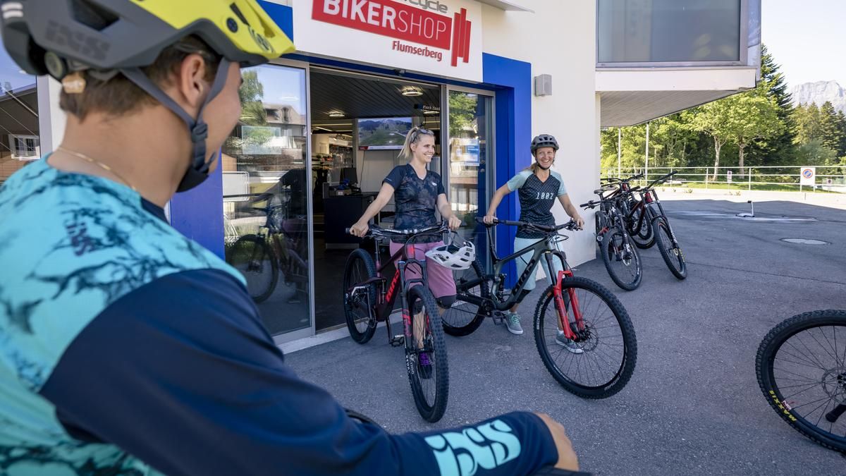 Zwei Personen mit Bike-Ausrüstung laufen aus dem BikerShop Flumserberg