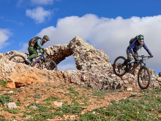 Zwei Biker fahren mit Bikes durch Ruine und versetzen das Hinterrad